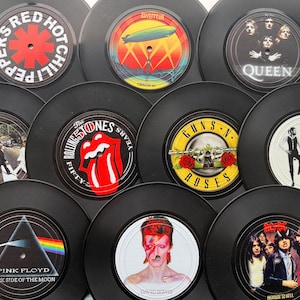 May include: A selection of black vinyl records showcasing album art from iconic rock bands. The records display artwork from Red Hot Chili Peppers, Led Zeppelin, Queen, The Rolling Stones, Guns N' Roses, and Pink Floyd's "Dark Side of the Moon" album.