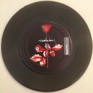 以下が含まれることがあります： 赤いバラと「violator」という文字が印刷された黒いビニールレコード。ラベルには「Depeche Mode」という文字も印刷されている。