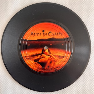 Könnte beinhalten: Schwarze Vinyl-Schallplatte mit dem Albumcover von Alice in Chains' "Dirt". Das Mittellabel zeigt eine orange-rote Landschaft mit einer Figur. Der Name der Band steht oben.