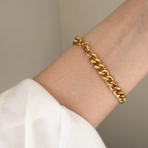 May include: A gold chain bracelet with a curb link design.