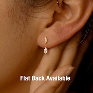 Peut inclure: Gros plan sur une oreille ornée de deux boucles d'oreilles dorées. La boucle d'oreille supérieure est un petit clou, et la boucle d'oreille inférieure présente une pierre précieuse en forme de marquise. Le texte "Flat Back Available" est visible.