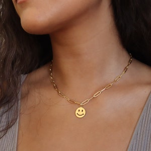 May include: A gold chain necklace with a gold smiley face pendant.