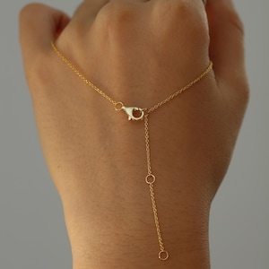 May include: A delicate gold necklace with a lobster clasp and an adjustable chain. The necklace features a fine chain with a small pendant and a simple, elegant design. The jewelry is displayed against a neutral background.