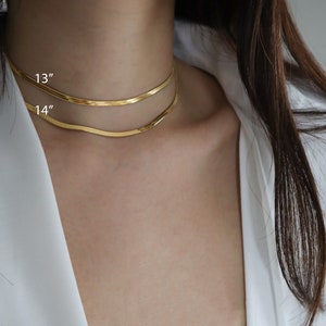 May include: Two gold chain necklaces, one 13 inches long and the other 14 inches long, layered on a person's neck.