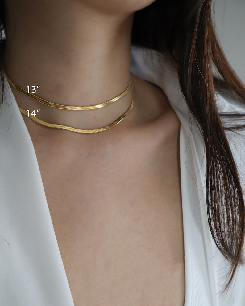 May include: Two gold chain necklaces, one 13 inches long and the other 14 inches long, layered on a person's neck.