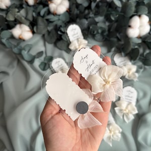 May include: Clear plastic favor boxes with white paper inserts and white ribbon bows. The boxes have the text "Sinem & Ahmet 01.02.2025 In Istanbul" printed on them.