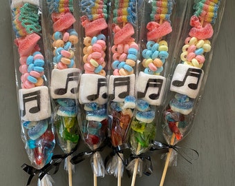 May include: Six colorful candy skewers with a musical note marshmallow on top. Each skewer is wrapped in clear plastic and tied with a black ribbon.