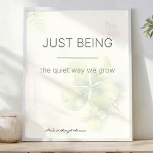Può includere: Una stampa incorniciata con le parole "JUST BEING" e "the quiet way we grow" in stile minimalista. L'opera presenta un quadrifoglio ed elementi botanici. Vasi decorativi e una pianta in vaso sono su una superficie di legno.