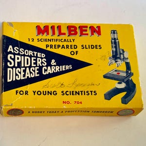 May include: A yellow rectangular box for a Milben microscope set containing 12 scientifically prepared slides of assorted spiders and disease carriers. The box features a black microscope illustration, the text No. 704, and the slogan A hobby today-a profession tomorrow.
