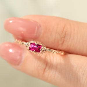 May include: A delicate gold ring with a vibrant pink gemstone set in a floral design.