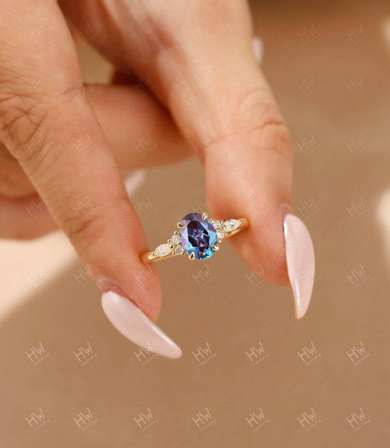 A gold engagement ring with an oval-shaped blue gemstone surrounded by smaller diamonds. The ring is set on a thin band.