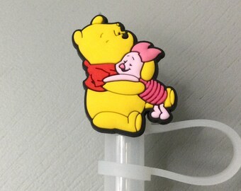 May include: A yellow Winnie the Pooh character figurine hugging a pink Piglet character figurine. The figurines are attached to a clear plastic straw.