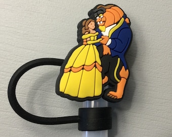 Puede incluir: Un soporte para pajitas de goma negra con una imagen de dibujos animados amarilla, naranja y azul de Bella y la Bestia de La Bella y la Bestia de Disney.