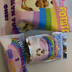 Könnte beinhalten: Drei Party-Geschenktüten mit einem Regenbogen-Design. Die Tüten sind mit einem Bild eines kleinen Mädchens und dem Text "Addilyn Turns One!" und "Chip Potato" verziert. Eine Tüte ist ein silberner Folienbeutel mit dem Text "Caprisun" und "Madilyn is Turning One!"