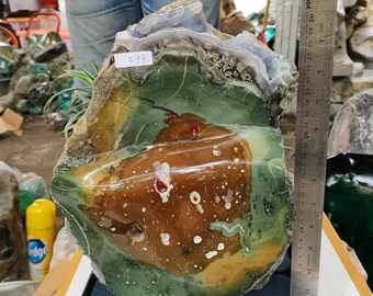 May include: A large, irregularly shaped stone with green, brown, and white hues. A ruler indicates a length of approximately 25 cm. The stone has a rough, natural texture. The item is likely a decorative piece, with a label showing the number 577.