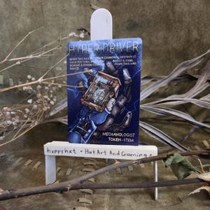 May include: A blue and gold Hyper Driver card with the text "Hyper Driver" at the top. The card features a mechanical arm holding a device with a clock face. The text "Mechanologist Token-Item" is at the bottom. The card is displayed on a white stand.