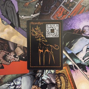 May include: A black card featuring a stylized deer with large antlers in a gold color. The card has the text "HxxpyHxt" and a QR code in the upper right corner. The card is surrounded by other cards with various illustrations.
