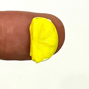Puede incluir: Un abalorio de rodaja de limón amarillo, perfecto para añadir un toque de verano a tus joyas o manualidades.