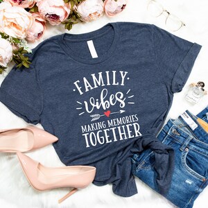 May include: A navy blue t-shirt with the text "FAMILY. vibes MAKING MEMORIES TOGETHER" in white lettering with a red heart and arrow graphic.