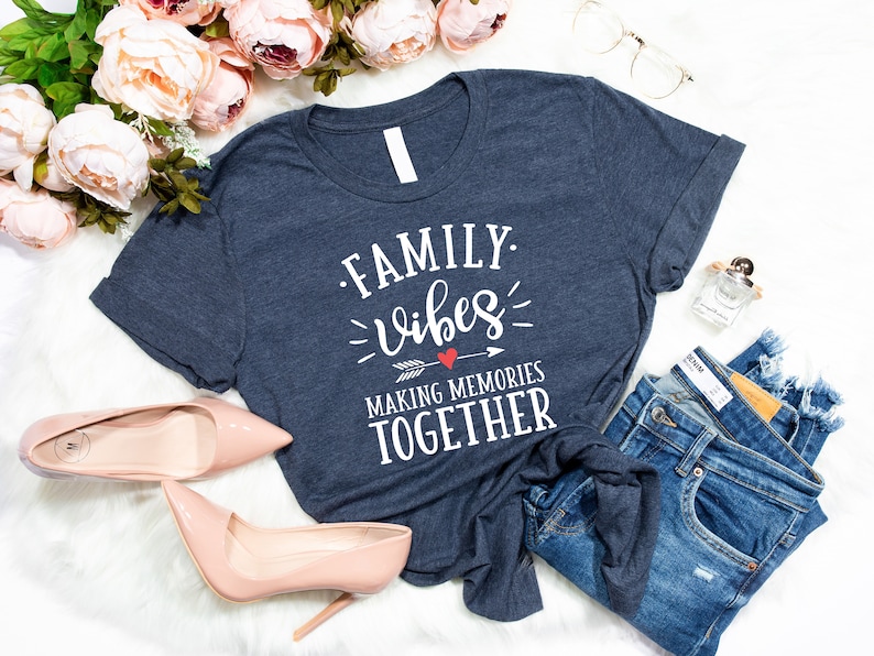 May include: A navy blue t-shirt with the text "FAMILY. vibes MAKING MEMORIES TOGETHER" in white lettering with a red heart and arrow graphic.