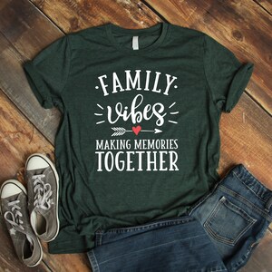 May include: A dark green t-shirt with the text "FAMILY vibes MAKING MEMORIES TOGETHER" in white lettering. A red heart and arrow are above the word "memories".