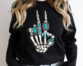 May include: Black sweatshirt with a skeleton hand making the peace sign. The hand is adorned with turquoise and silver jewelry.
