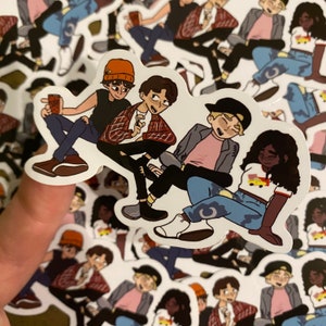 May include: Four cartoon characters, two male and two female, are depicted in a sticker. The characters are wearing casual clothing and are sitting together. The sticker is white with a black outline.