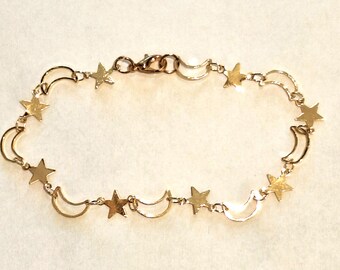 Puede incluir: Pulsera dorada con dijes de estrellas y medias lunas. La delicada cadena une las formas celestiales, creando un accesorio caprichoso y elegante. La pulsera está diseñada con un cierre de mosquetón.