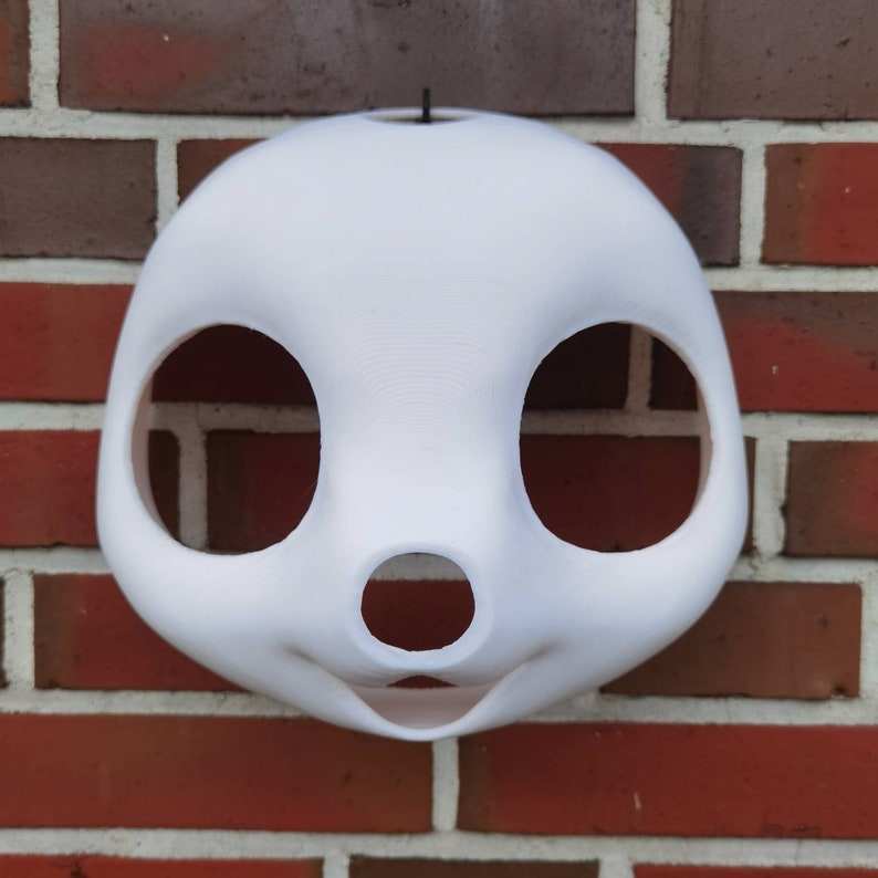 May include: White unfinished furry animal mask with large eye holes and a small nose hole. The mask is made of a smooth, hard material and has a hole at the top for attaching a strap.