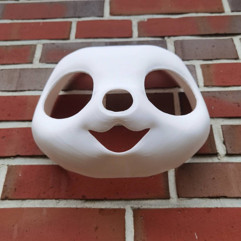 May include: White unpainted panda mask with cutouts for eyes, nose, and mouth. The mask is made of a smooth, hard material.