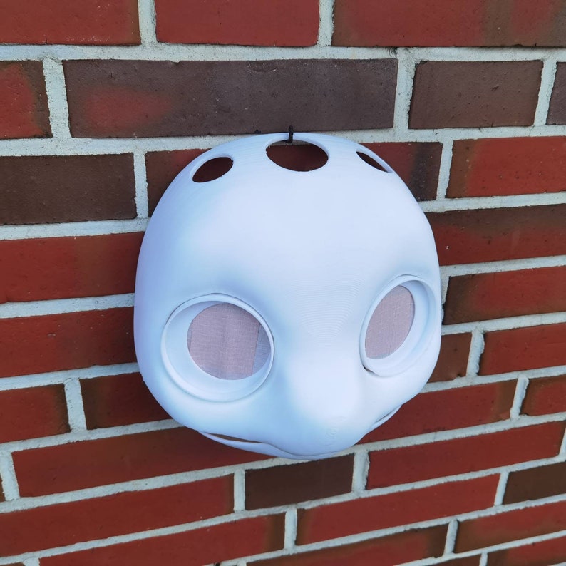 May include: White unfinished furry animal mask with large eye holes and a small nose hole. The mask is made of a smooth, hard material and has a textured surface.