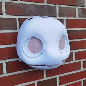 May include: White unfinished furry mask with two large eye holes and a small nose hole. The mask is made of a smooth, hard material and is ready for painting.