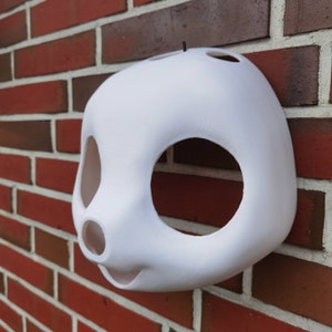 May include: White unfinished plastic mask with large eye holes and a small nose hole. The mask is shaped like an animal face.
