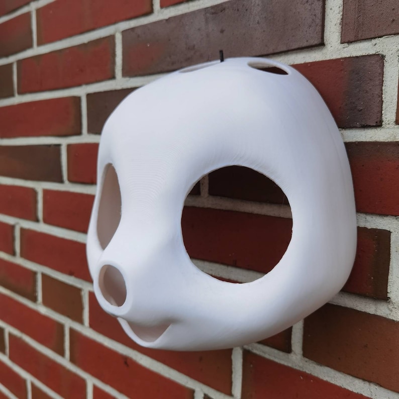 May include: White unfinished plastic mask with large eye holes and a small nose hole. The mask is shaped like an animal face.