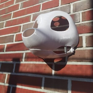 May include: White furry animal mask with a spring attached to the side. The mask is made of a smooth, hard material and has a large, open mouth.