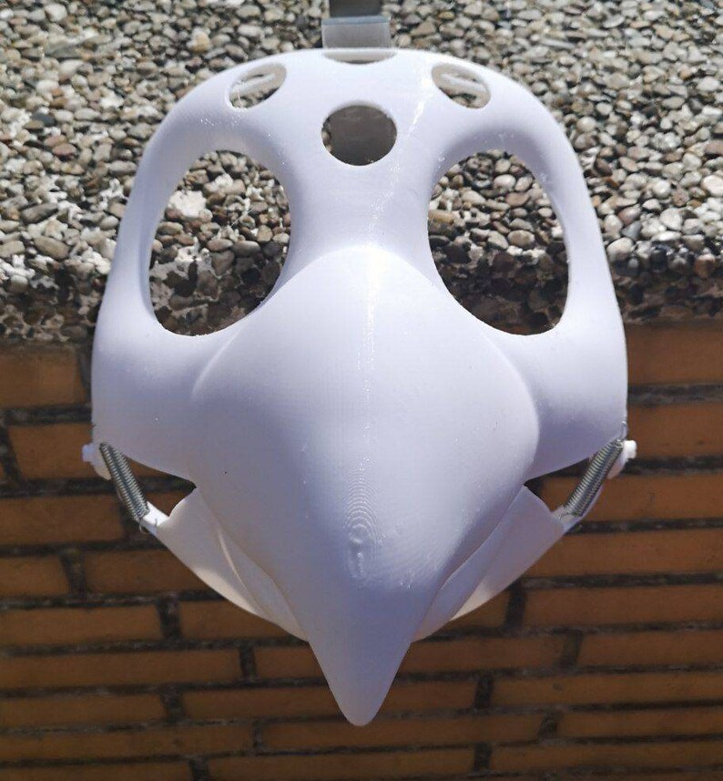 May include: White plastic mask with a bird-like beak and multiple holes for eyes and nose. The mask is designed to be worn over the face.
