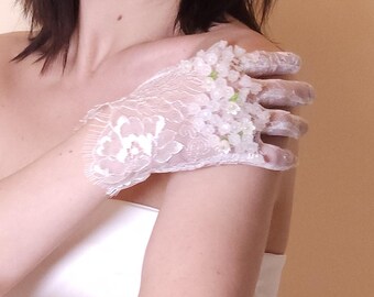 May include: A white lace glove with floral embellishments on the back of the hand.