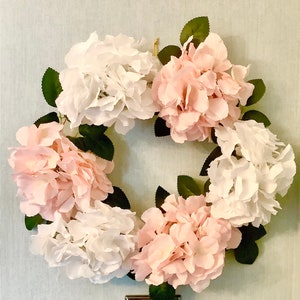 Könnte beinhalten: Ein Kranz aus rosa und weißen Hortensienblüten mit grünen Blättern.