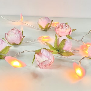 May include: A string of fairy lights with pink flower accents. The lights are shaped like hearts and emit a warm glow.
