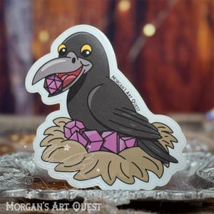 May include: A black crow with a purple gemstone in its beak sits in a nest of purple crystals. The crow is smiling and has a white background. The sticker says "Morgan's Art Quest".
