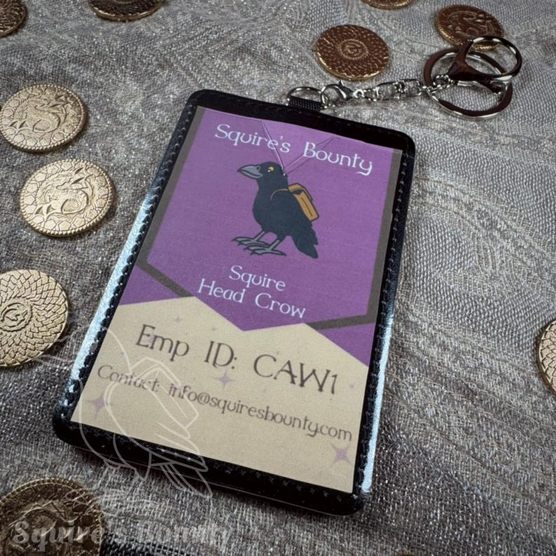 May include: A black and purple Squire's Bounty employee ID badge with a crow illustration and the text "Squire Head Crow." The badge is attached to a silver keychain. Gold coins are scattered around the badge.