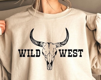 May include: A beige sweatshirt with a black bull skull graphic and the text "WILD WEST" printed on the front.
