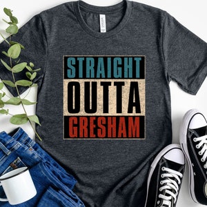 May include: Heather dark grey t-shirt with the text "STRAIGHT OUTTA GRESHAM" in a vintage style with red, white, and blue colours.