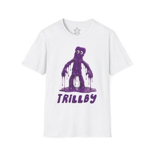 May include: White t-shirt featuring a purple cartoon character with the word "TRILLBY" in purple text. The character appears to be made of a dripping, viscous substance.