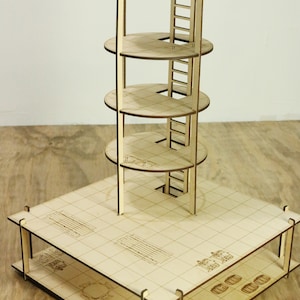 Pu&ograve; includere: Una torre di legno con cinque livelli e una scala. La torre &egrave; realizzata in legno tagliato al laser e ha una base quadrata. La torre &egrave; su una superficie di legno.