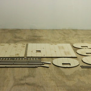 Pu&ograve; includere: Un set di pezzi di legno tagliati al laser per costruire un modello. I pezzi sono di varie forme e dimensioni, tra cui quadrati, cerchi e rettangoli. I pezzi sono in legno marrone chiaro.