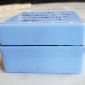 May include: A light blue plastic box with the text "Riverhead Savings Bank Riverhead, N.Y. Member F.D.I.C." printed on the top.