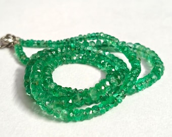 Pode incluir: Um colar de esmeraldas verde vibrante com fecho prateado. O colar é composto por pequenas contas de esmeralda facetadas, unidas para formar uma joia delicada e atraente. As contas são de uma cor verde rica e saturada.