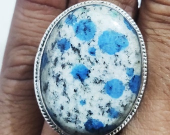 May include: A silver ring featuring a large oval blue and white gemstone. The gemstone has a speckled pattern with blue spots on a white background.