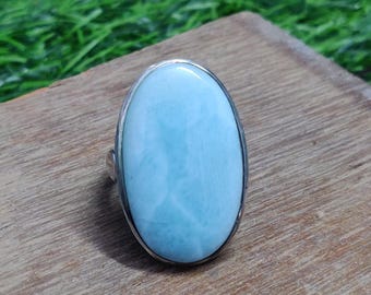 Op de afbeelding: Een zilveren ring met een grote ovale blauwe edelsteen. De edelsteen heeft een bewolkte, gemarmerde uitstraling.